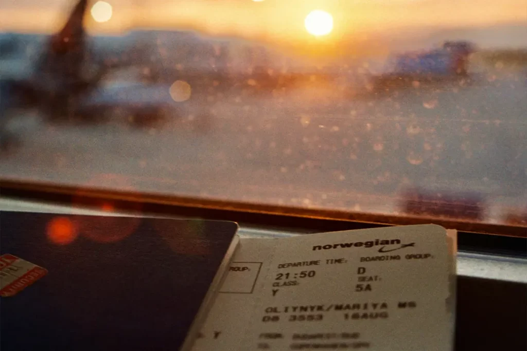 Airline ticket from Norwegian Airlines tucked into a passport with a blurred airline background.